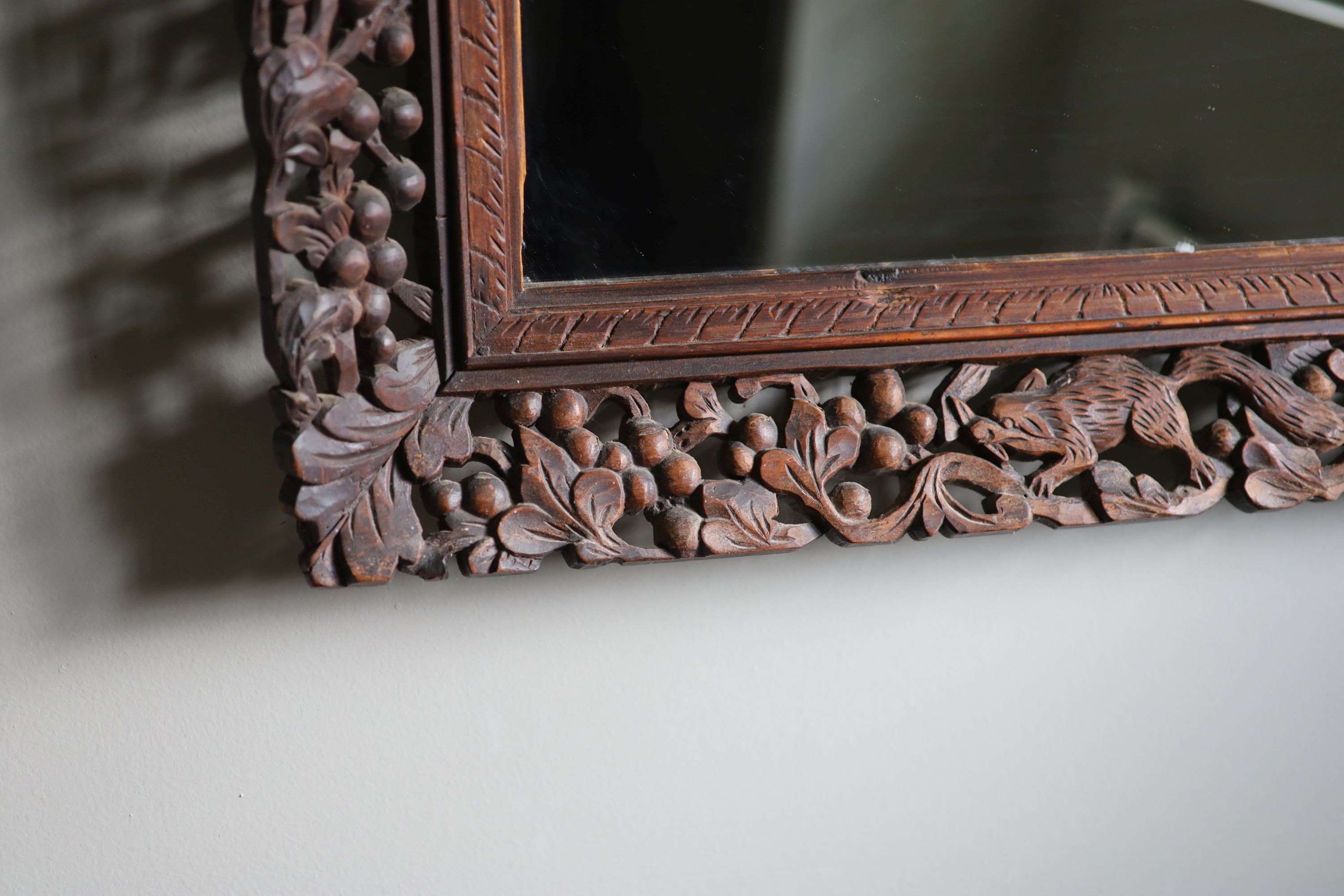 A Continental hardwood wall mirror, carved and pierced with squirrels and fruit, width 77cm height 63cm